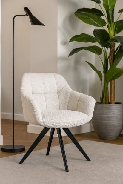 Crèmekleurige draaistoel met zachte bekleding, zwarte metalen poten en een moderne look in een interieursetting.