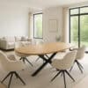 Deens Ovale mangohouten eettafel met zwarte kruispoot en zes beige draaistoelen in lichte moderne woonkamer.”
